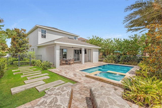 rear view of house with ceiling fan, a yard, a patio, and a pool with hot tub