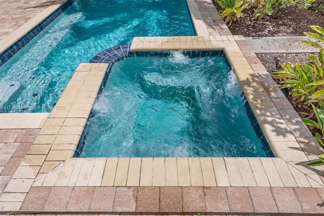 view of pool featuring pool water feature and an in ground hot tub