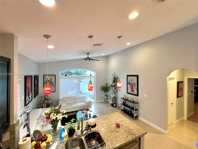 kitchen featuring light stone countertops, sink, ceiling fan, and pendant lighting