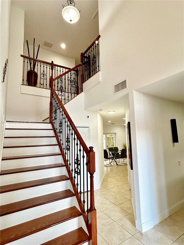 stairs featuring tile patterned floors and a towering ceiling