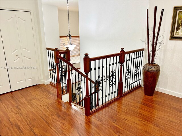 stairs featuring hardwood / wood-style floors and a chandelier