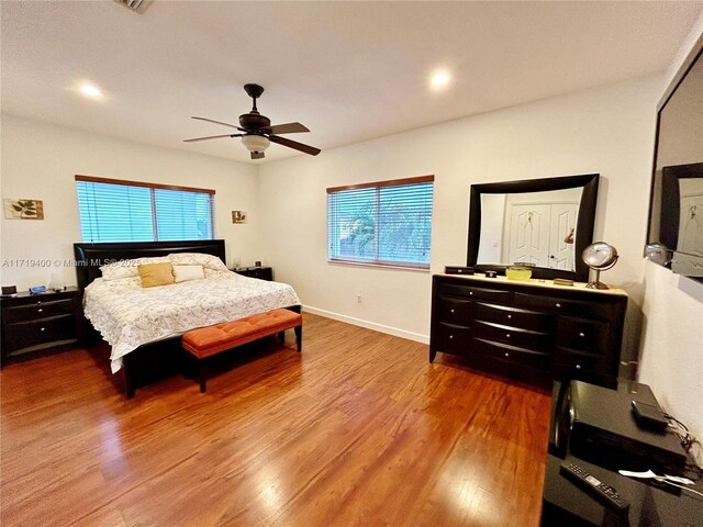 bedroom featuring multiple windows, hardwood / wood-style flooring, and ceiling fan