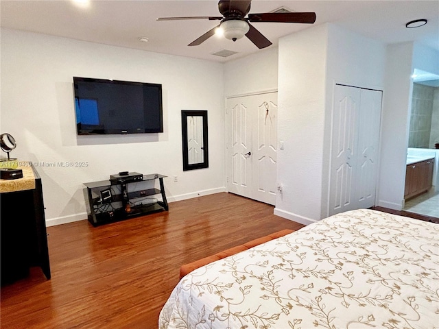 bedroom featuring dark wood-type flooring, two closets, and ceiling fan