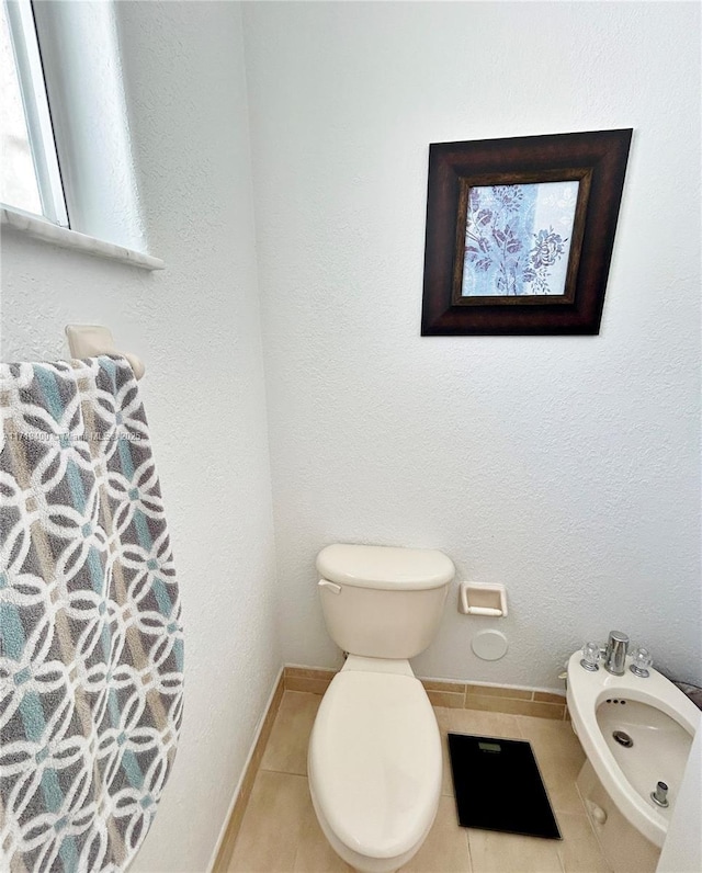 bathroom with toilet, tile patterned floors, and a bidet