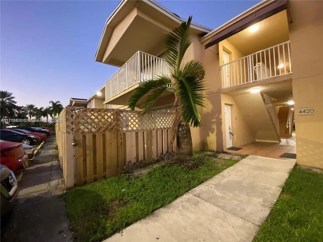 property exterior at dusk featuring a balcony