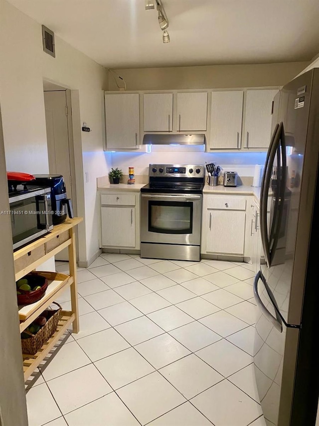 kitchen featuring appliances with stainless steel finishes, rail lighting, and light tile patterned flooring