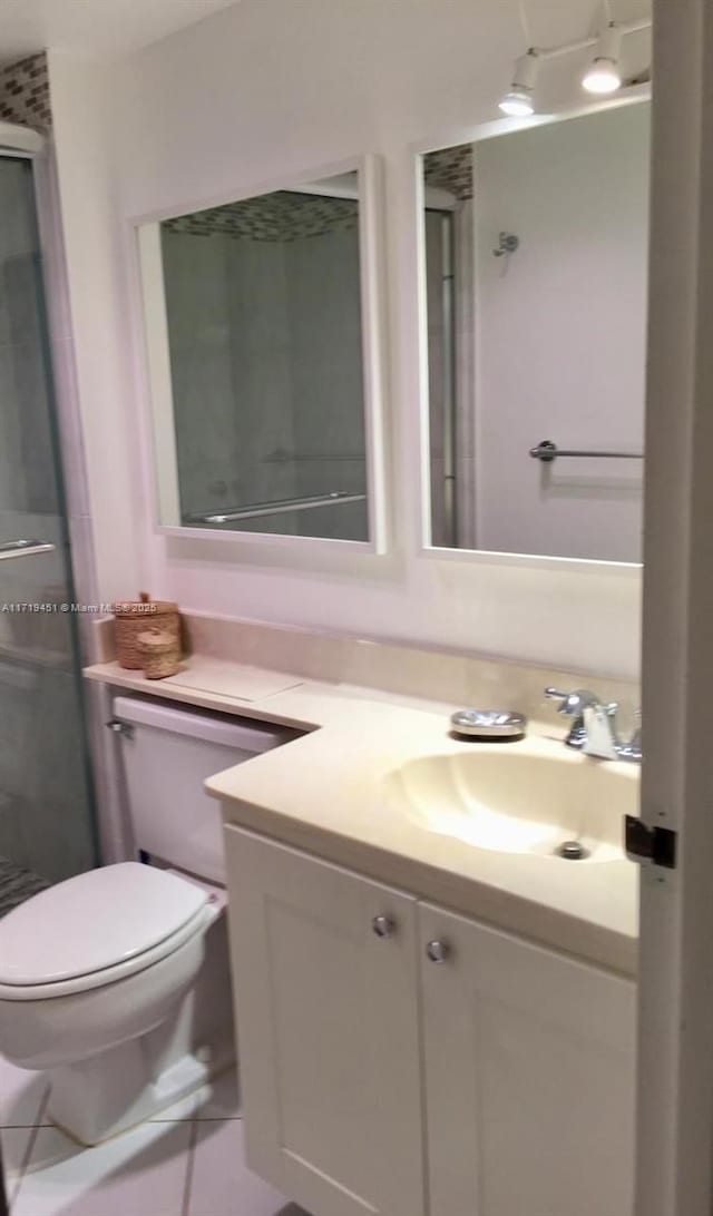 bathroom with tile patterned flooring, vanity, toilet, and walk in shower