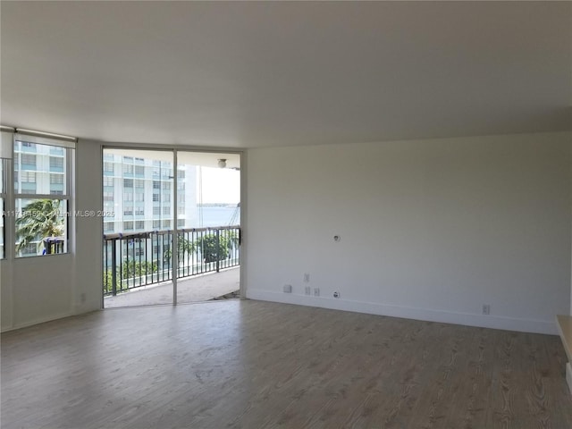 unfurnished room with expansive windows and dark wood-type flooring