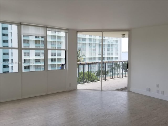 empty room with floor to ceiling windows and hardwood / wood-style floors