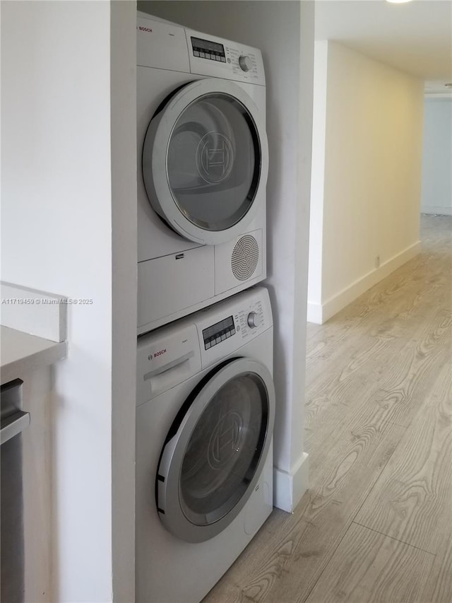 clothes washing area with light hardwood / wood-style flooring and stacked washer / dryer