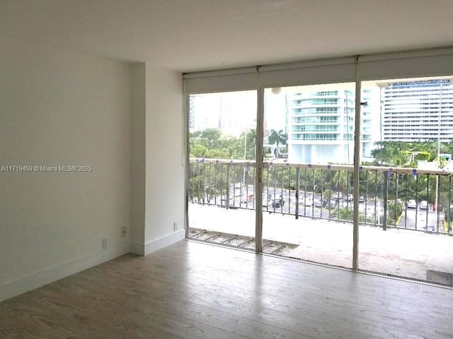 unfurnished room featuring hardwood / wood-style flooring, expansive windows, and a healthy amount of sunlight