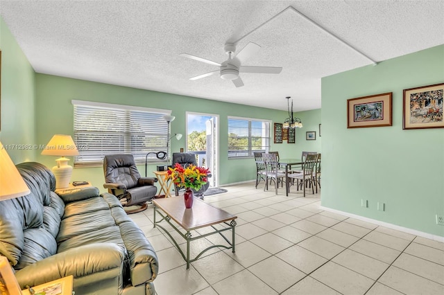 living room with ceiling fan, light tile patterned flooring, and a textured ceiling