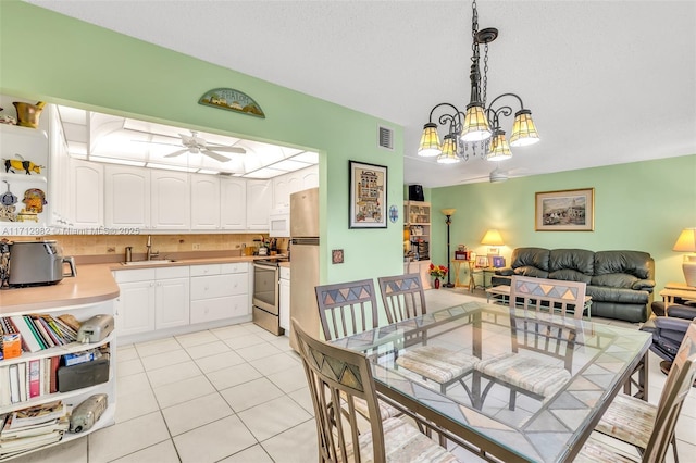 tiled dining room with a textured ceiling, ceiling fan with notable chandelier, and sink