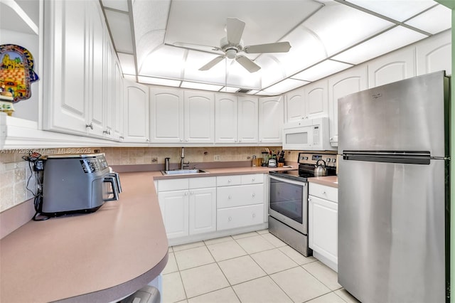 kitchen with sink, white cabinets, light tile patterned floors, and appliances with stainless steel finishes