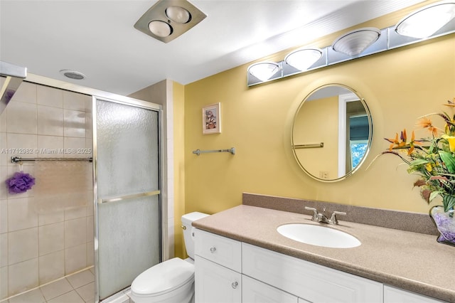 bathroom with tile patterned flooring, vanity, toilet, and a shower with door