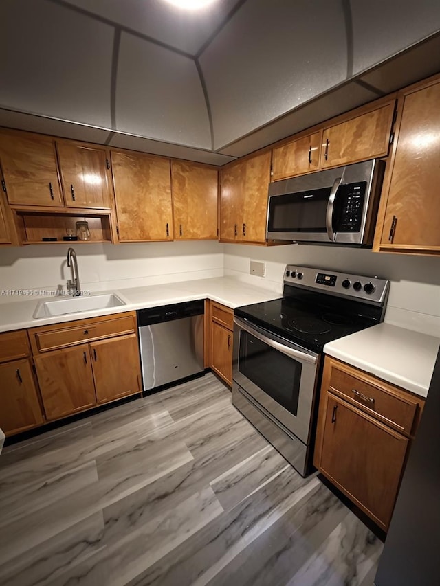 kitchen with sink, appliances with stainless steel finishes, and light hardwood / wood-style flooring