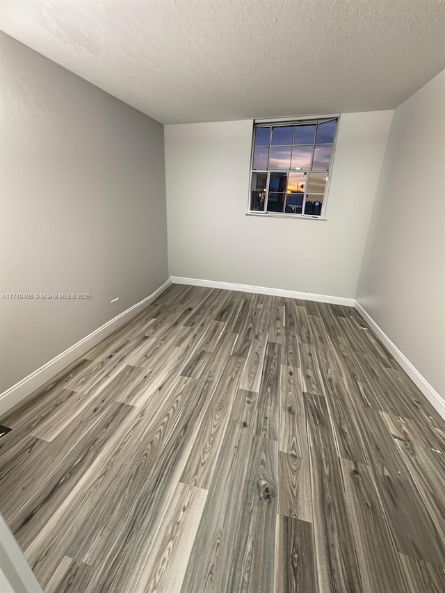 empty room featuring dark hardwood / wood-style flooring and a textured ceiling