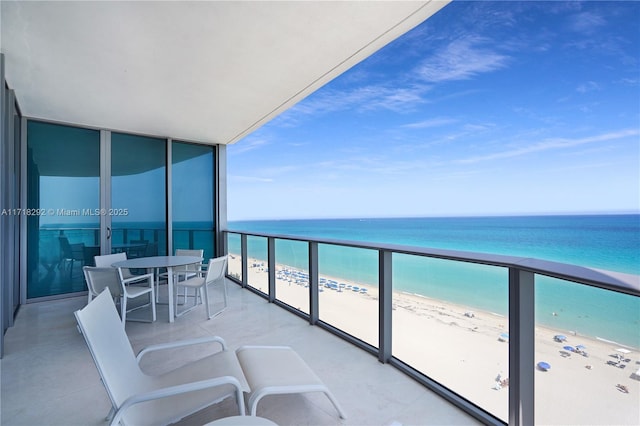 balcony featuring a view of the beach and a water view