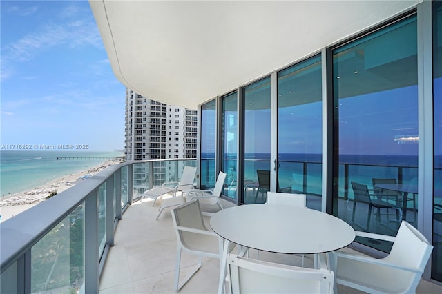 balcony with a water view and a view of the beach