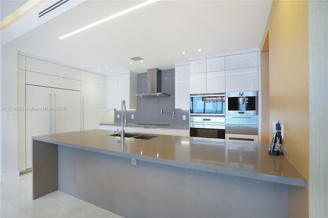 kitchen with black electric cooktop, white cabinetry, sink, and wall chimney exhaust hood