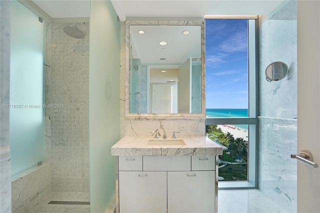 bathroom featuring a tile shower, decorative backsplash, vanity, and a healthy amount of sunlight