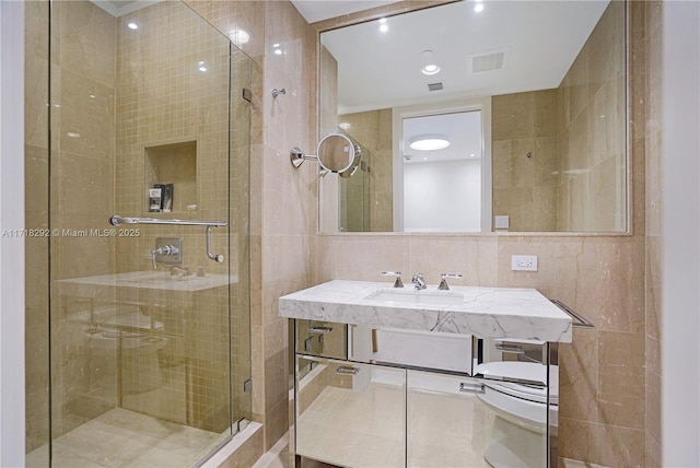 bathroom with vanity, toilet, tile walls, and a shower with shower door