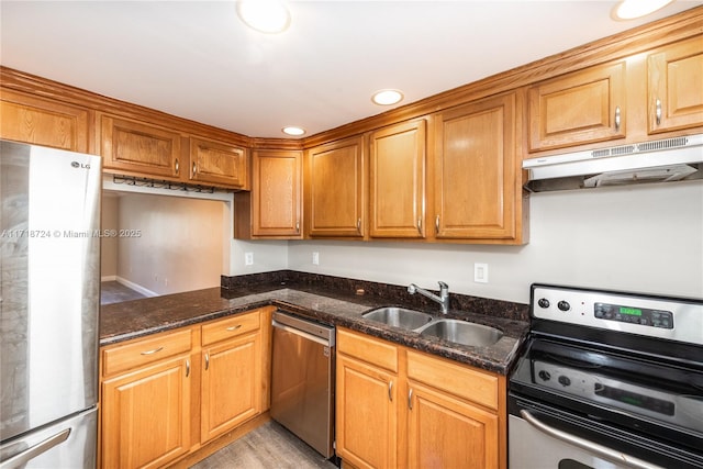 kitchen featuring dark stone countertops, sink, stainless steel appliances, and light hardwood / wood-style floors