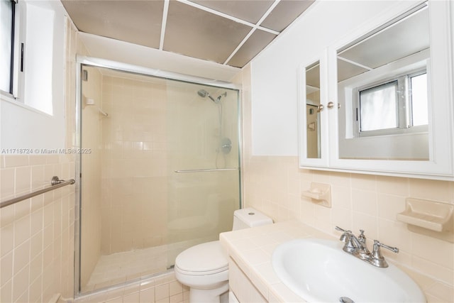 bathroom with vanity, a shower with shower door, tile walls, and toilet