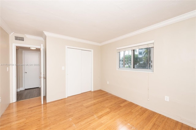 unfurnished bedroom with hardwood / wood-style floors, a closet, and crown molding