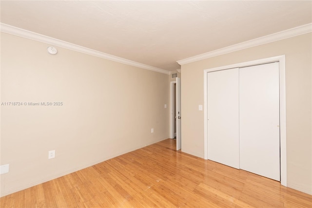 unfurnished bedroom with light wood-type flooring, a closet, and crown molding