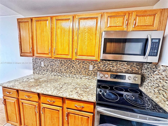 kitchen featuring decorative backsplash, light stone counters, light tile patterned floors, and appliances with stainless steel finishes