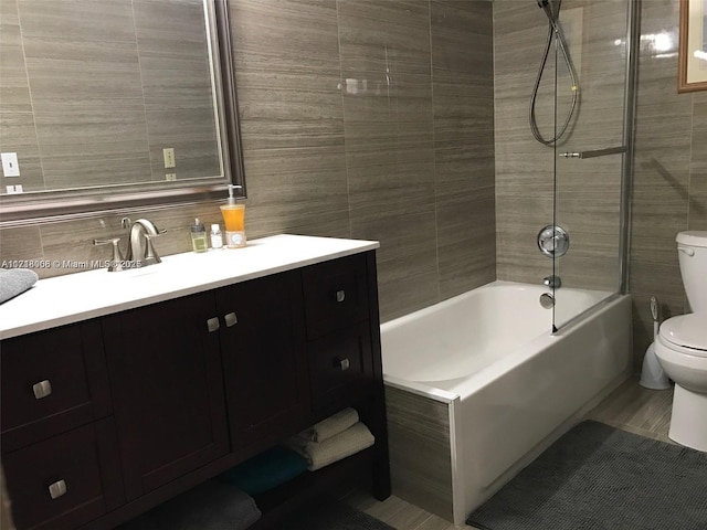 full bathroom featuring tiled shower / bath combo, toilet, decorative backsplash, vanity, and tile walls