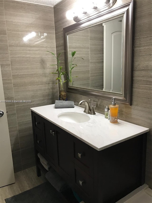 bathroom featuring vanity and tile walls