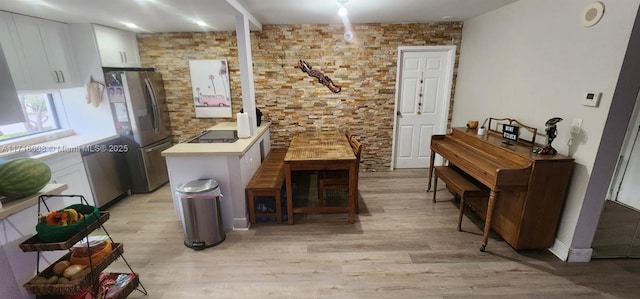 interior space featuring light hardwood / wood-style floors, white cabinetry, stainless steel refrigerator, and black electric cooktop