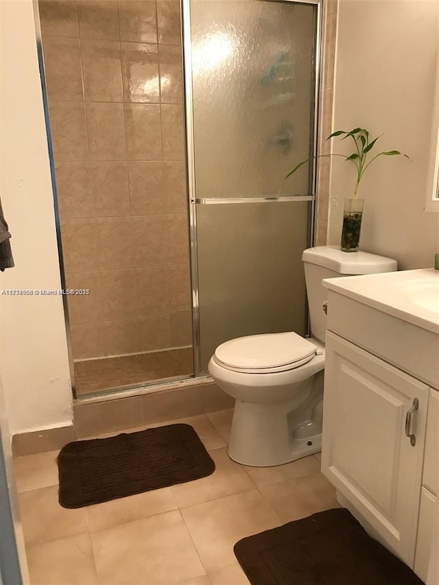 bathroom with tile patterned floors, a shower with door, vanity, and toilet