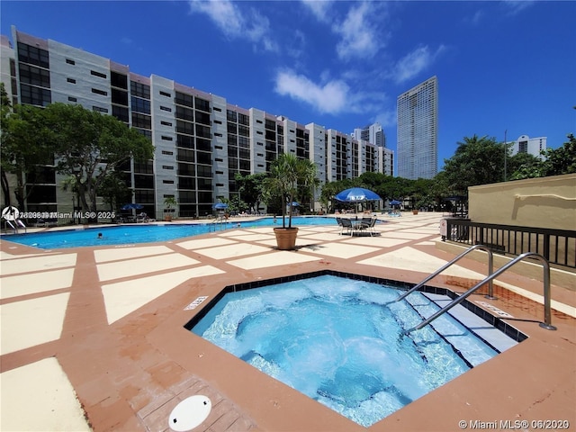 view of swimming pool featuring a hot tub and a patio area