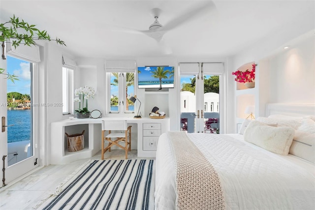 bedroom with access to outside, ceiling fan, and a water view