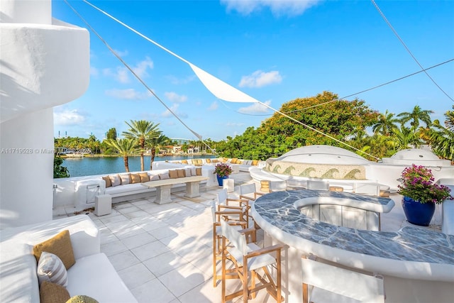 view of patio featuring exterior bar, an outdoor hangout area, and a water view