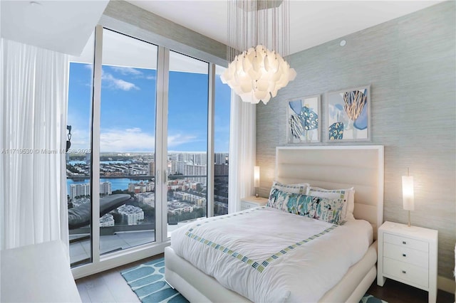 bedroom with access to exterior, wood-type flooring, a water view, and multiple windows