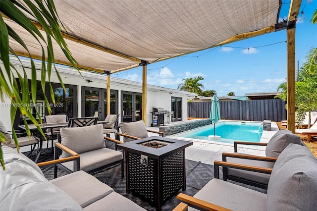 view of pool with an outdoor living space with a fire pit, grilling area, pool water feature, and a patio