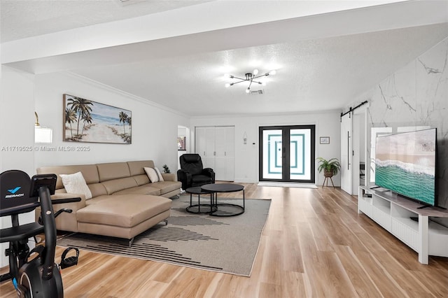 living room with a textured ceiling, light hardwood / wood-style flooring, ornamental molding, and french doors