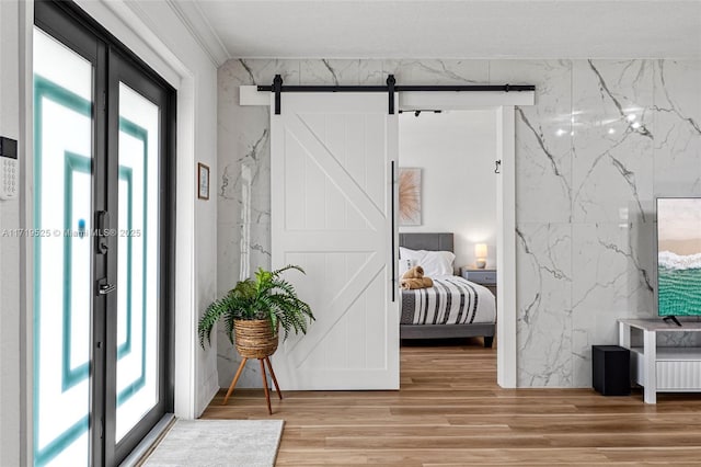 bedroom with a barn door and hardwood / wood-style flooring