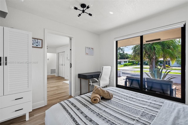 bedroom with a textured ceiling, hardwood / wood-style flooring, and access to outside