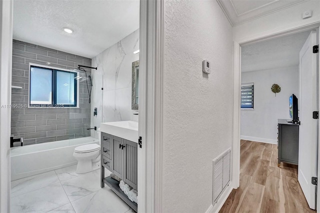 full bathroom with toilet, vanity, tiled shower / bath combo, ornamental molding, and a textured ceiling