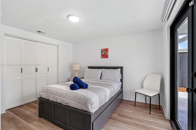 bedroom with a textured ceiling, a closet, and light hardwood / wood-style flooring