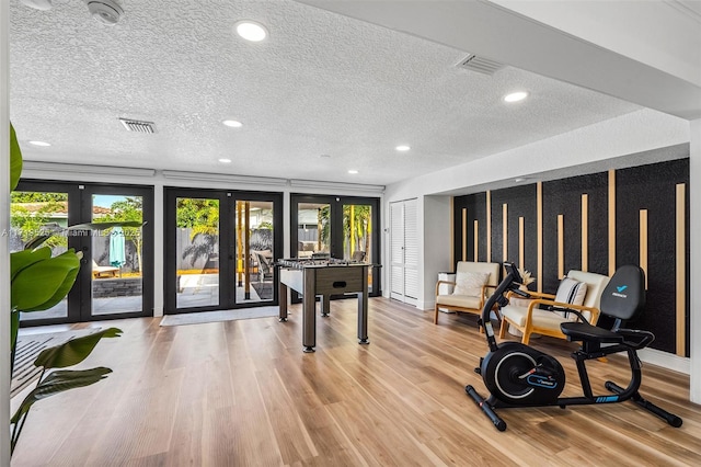 recreation room featuring french doors, plenty of natural light, and a textured ceiling