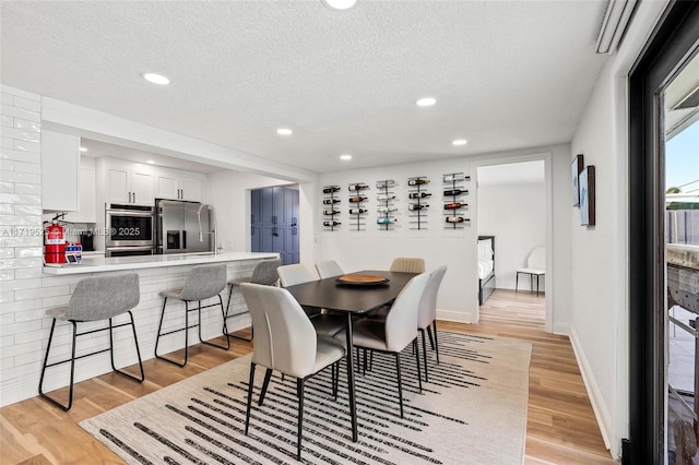 dining space with a textured ceiling and light hardwood / wood-style floors