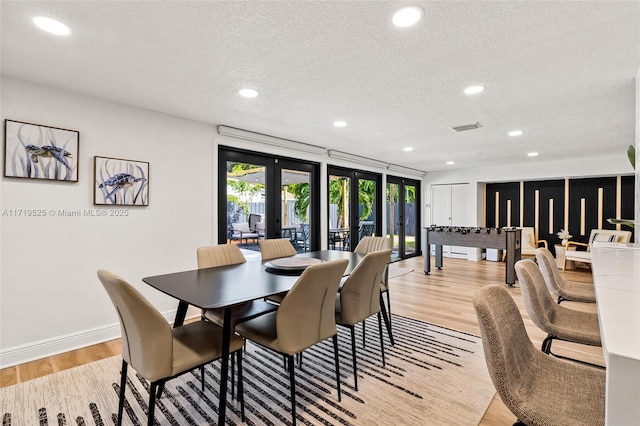 dining area with french doors, a textured ceiling, and light hardwood / wood-style flooring