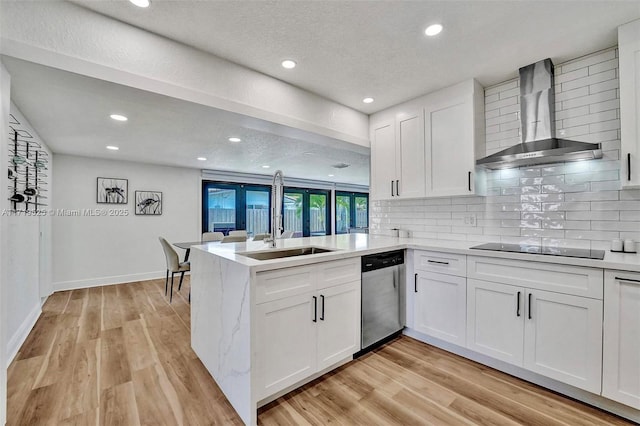 kitchen with dishwasher, white cabinetry, wall chimney range hood, sink, and kitchen peninsula