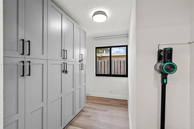 hall with light wood-type flooring and a textured ceiling